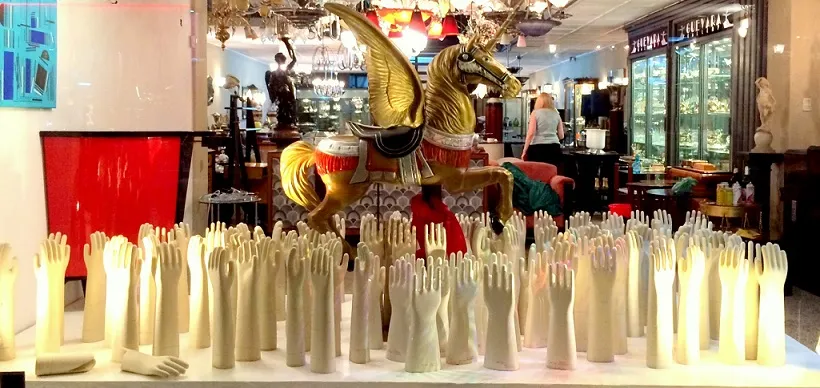 Vitrine mit weißen Keramikhänden und einem goldenen Pferd.