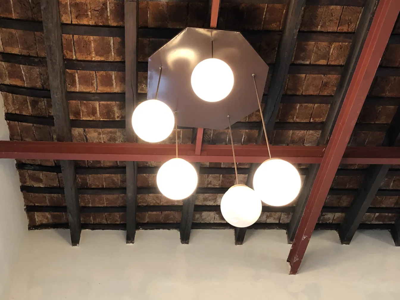 Quatro lâmpadas de teto antigas com globos brancos em um ambiente rústico.