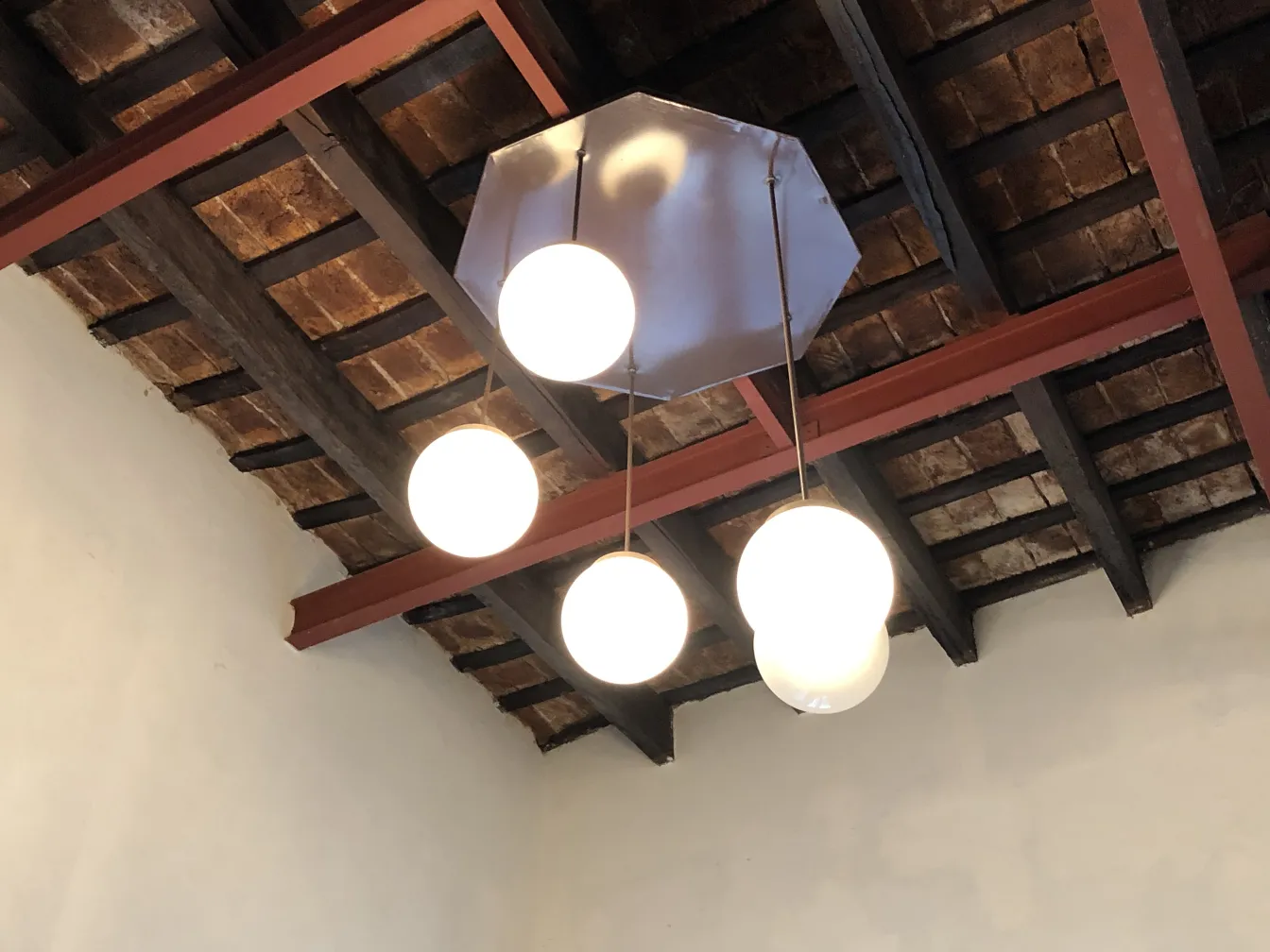 4 lâmpadas de teto antigas com esferas brancas em um ambiente acolhedor