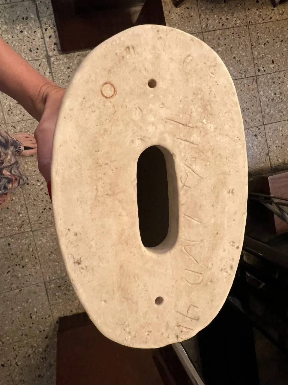 Vista superior de una escultura de cerámica antigua con forma ovalada.