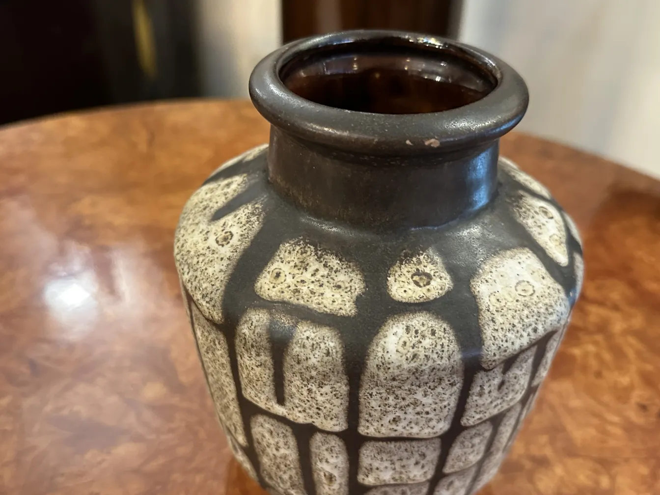 Antike Keramikflasche mit strukturiertem Design in hellen und dunklen Tönen auf einem Holztisch