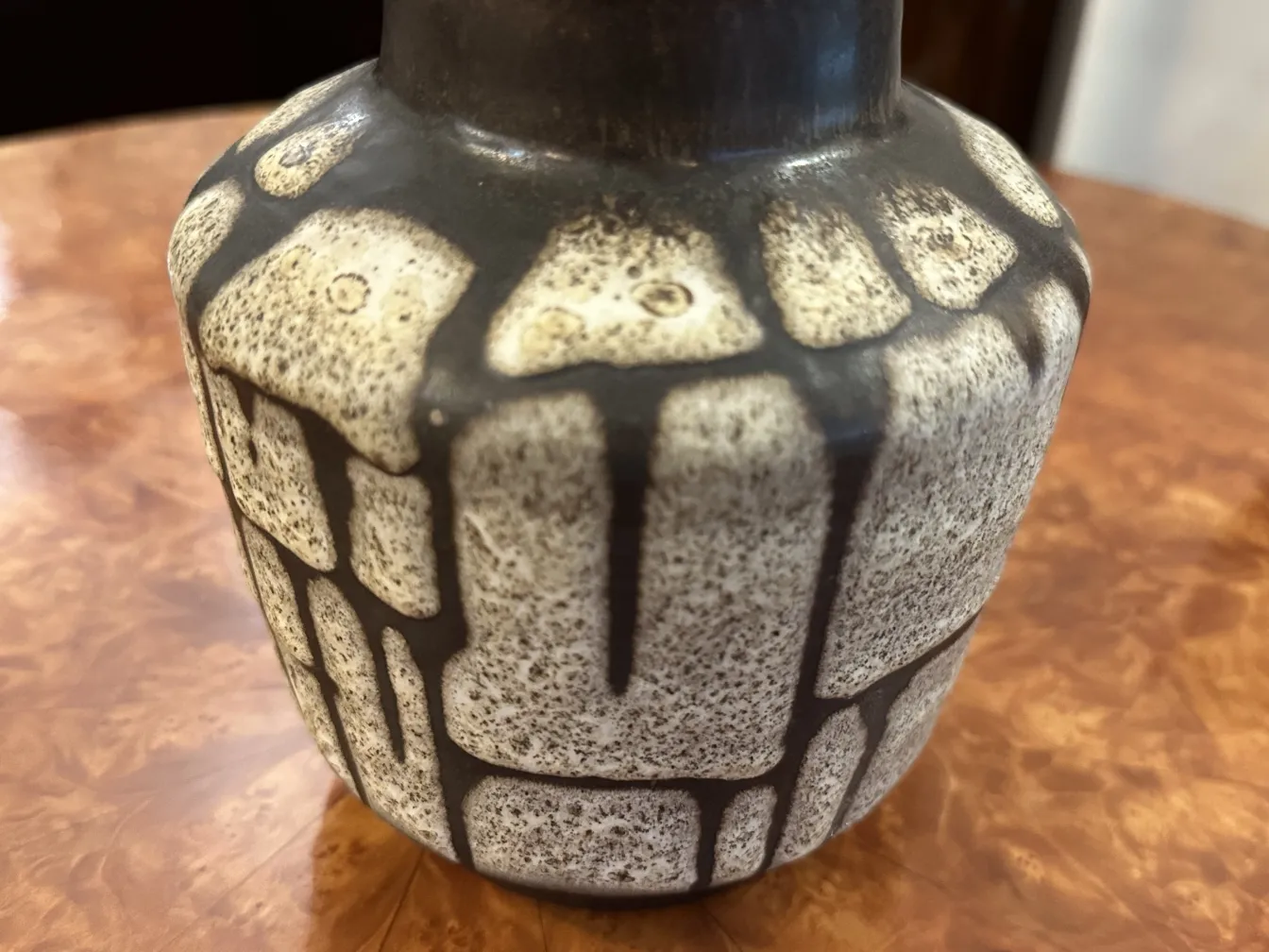 Antique ceramic vase with irregular texture and unique designs on a dark background.