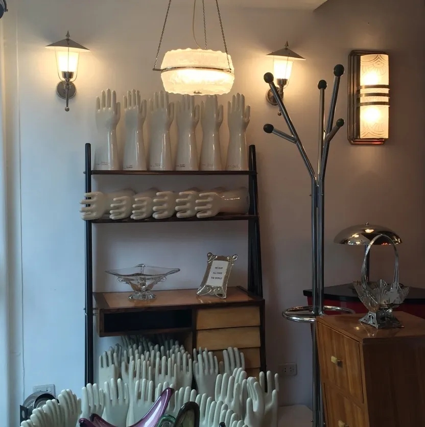 Scrivania antica con mani decorative e atmosfera eclettica.