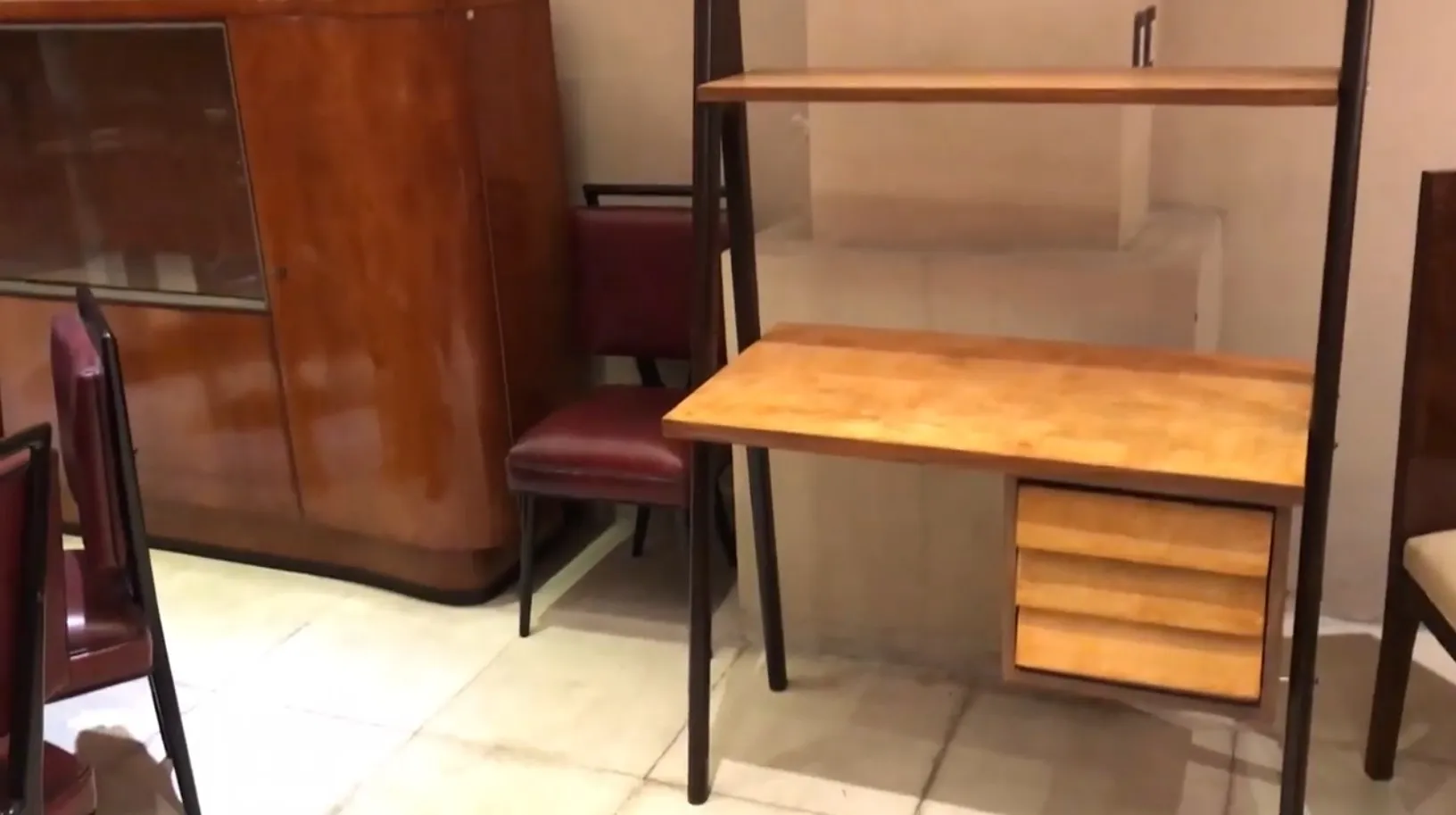 Escritorio antiguo de madera con estantes y cajones. Ambiente acogedor con sillas.