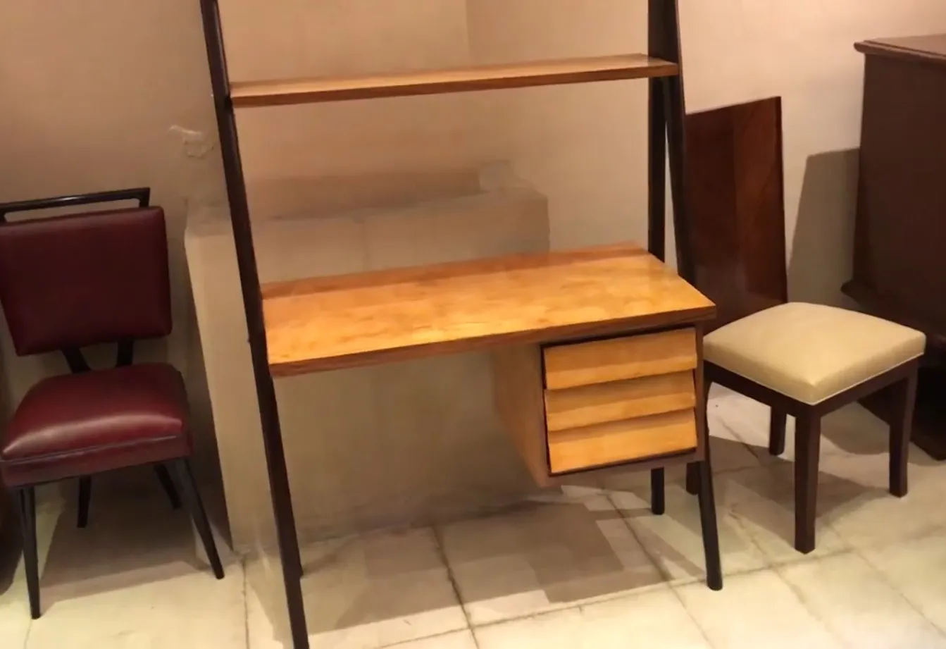 Escritorio antiguo de madera con estantería y cajones, entorno acogedor.