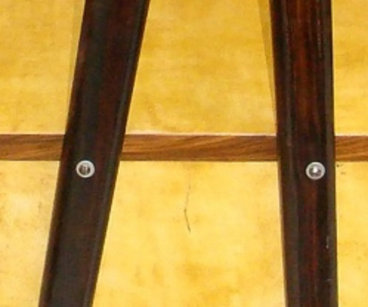 Ansicht eines antiken Schreibtisches mit sichtbaren Metallen und einer gelben Wand im Hintergrund.