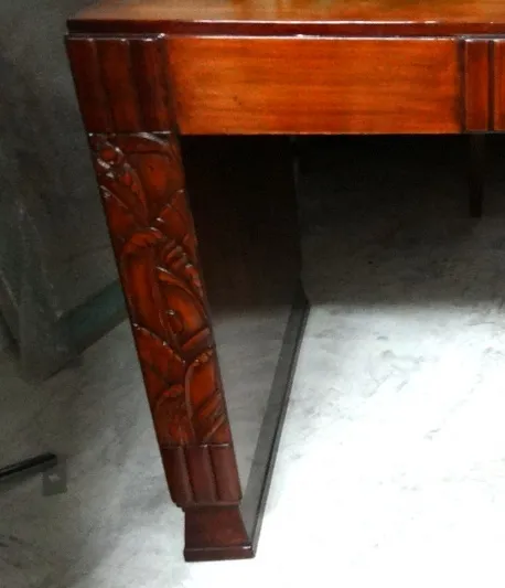 scrivania antica con dettagli scolpiti sulle gambe, sfondo neutro.