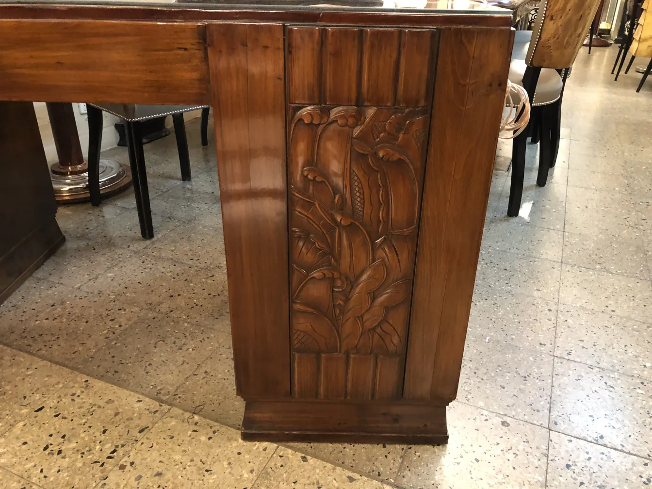 古い木製デスクの側面に装飾レリーフがあり、温かい雰囲気。