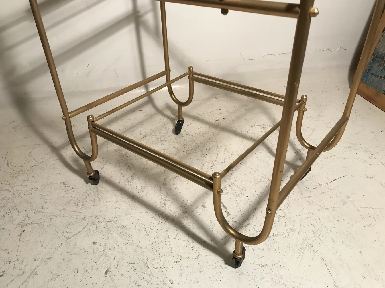 Mesa carrito antigua dorada con ruedas, estilo elegante.