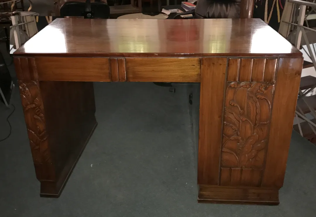 Escritorio antiguo de madera con tallados decorativos en los lados.