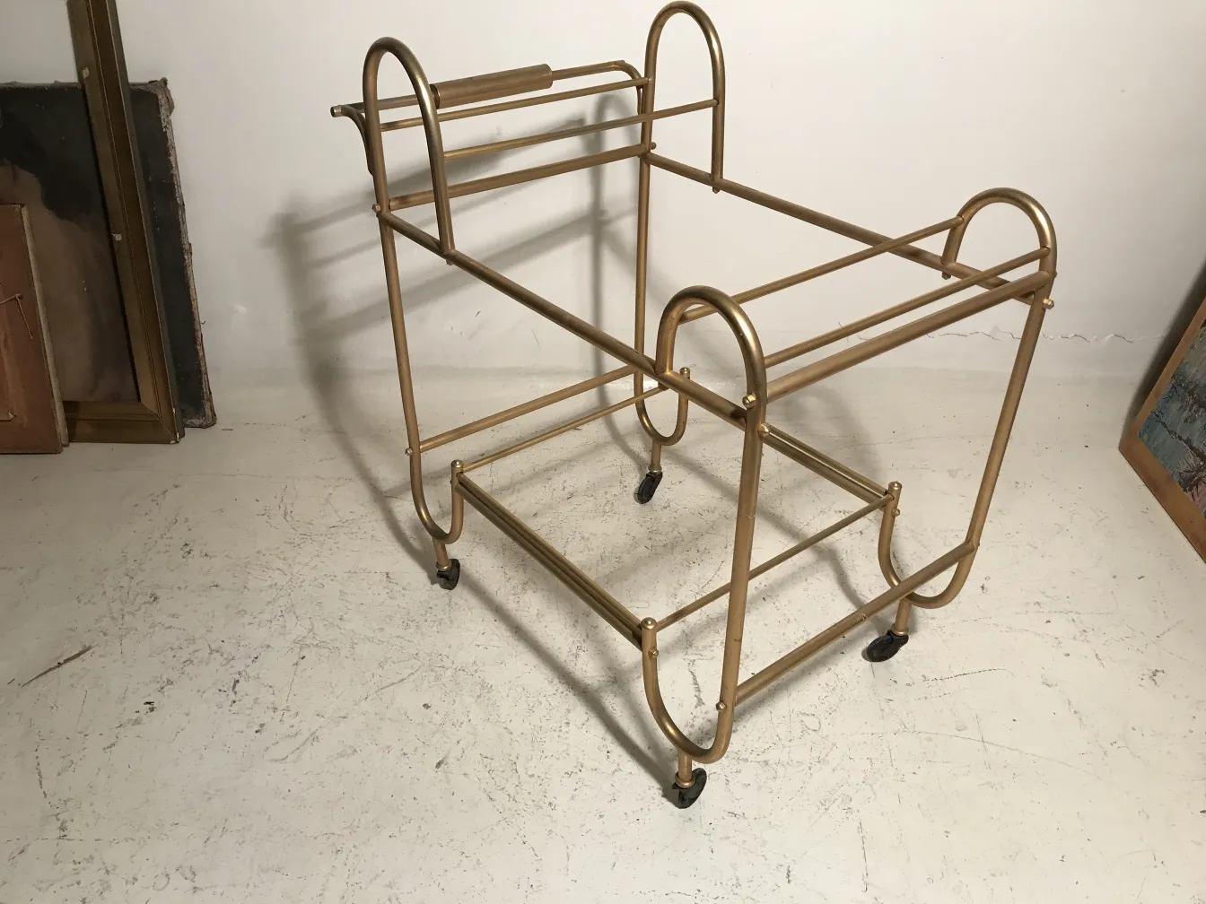 Carrello per cocktail antico dorato con ruote in un ambiente decorativo.