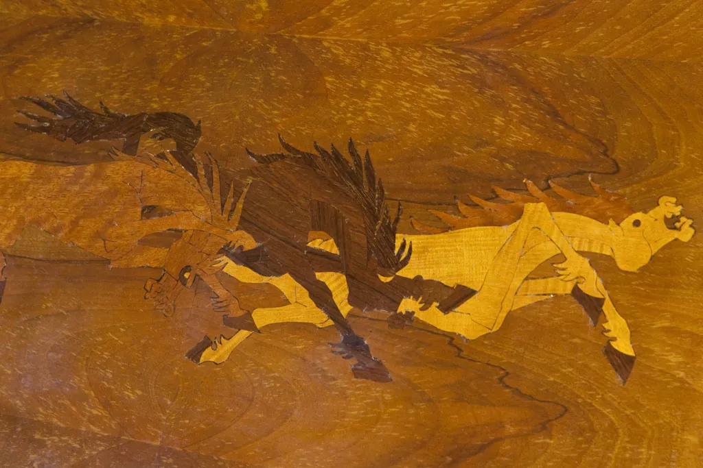 Madera de escritorio antiguo con un diseño artesanal representando escenas de caza.