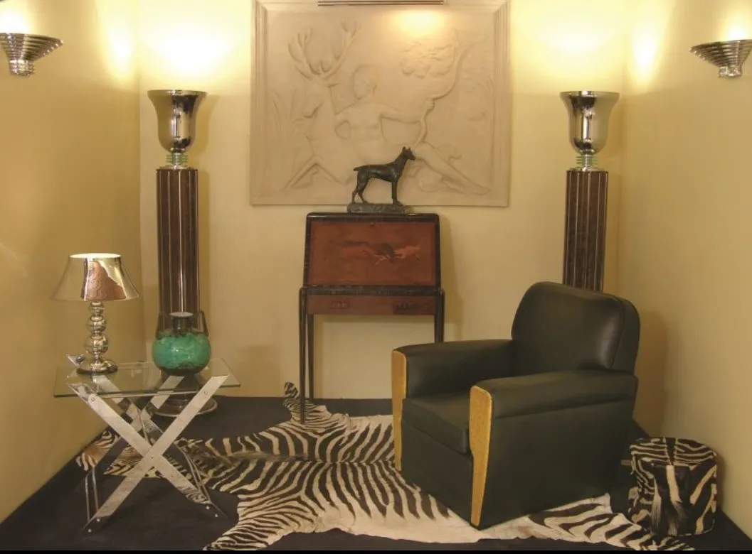 Scrivania antica in un ambiente elegante con lampade e una sedia.