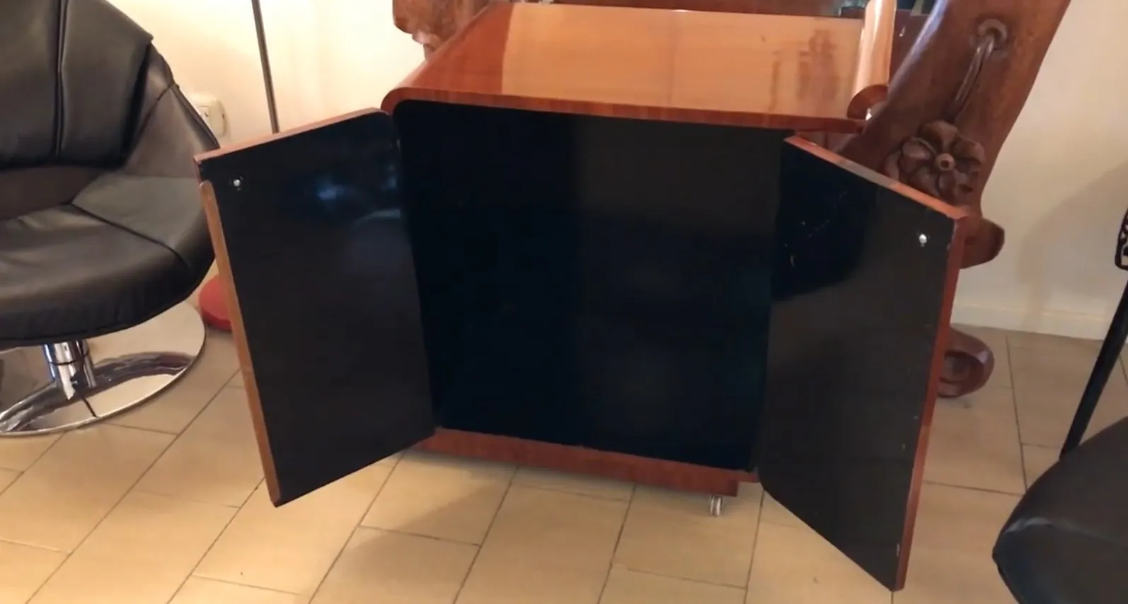 Antique cocktail trolley with black doors and shiny finish.