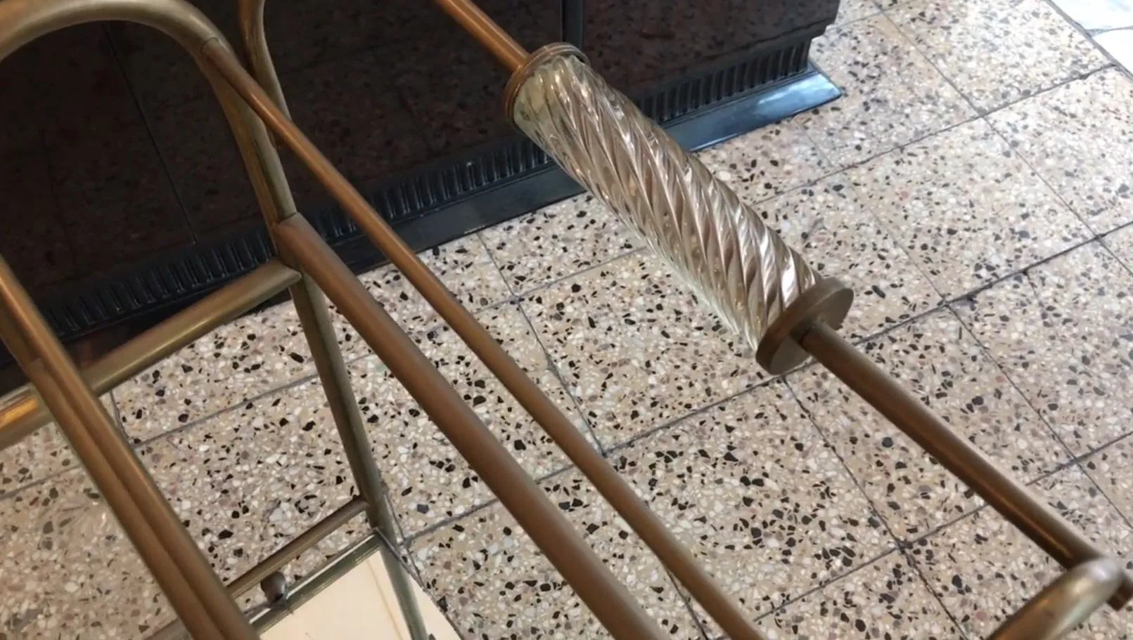 Mesa carrito antigua con manijas de cristal y estructura dorada en ambiente elegante.