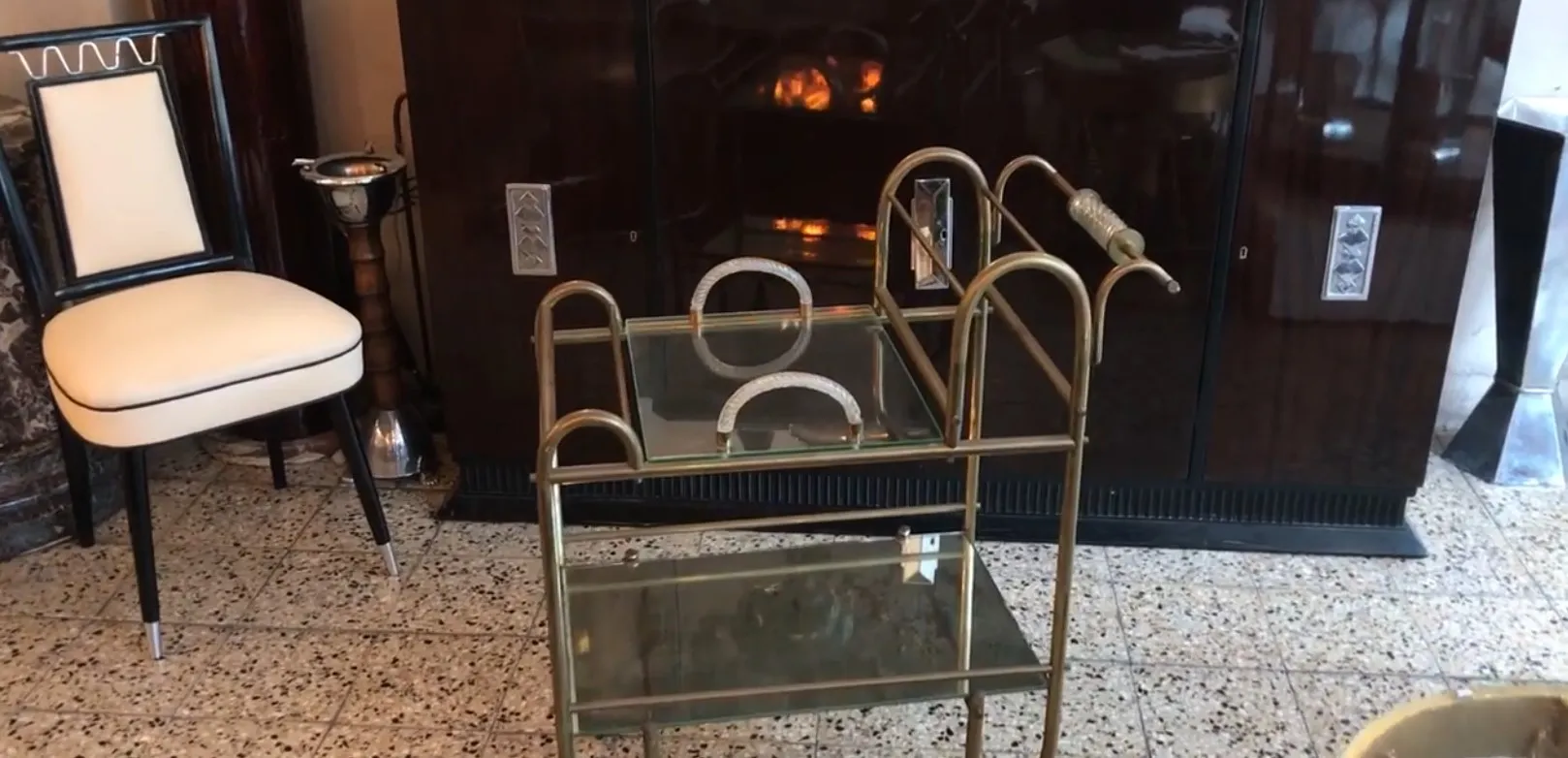 Carrello per cocktail antico con dettagli in vetro e metallo in un ambiente classico.