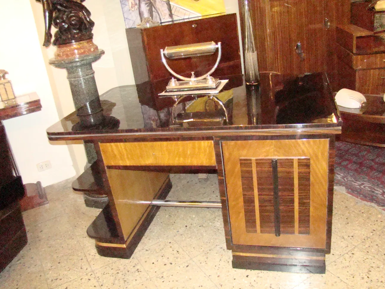 Escritorio antigo com design elegante e acabamentos brilhantes, cercado por móveis de madeira.