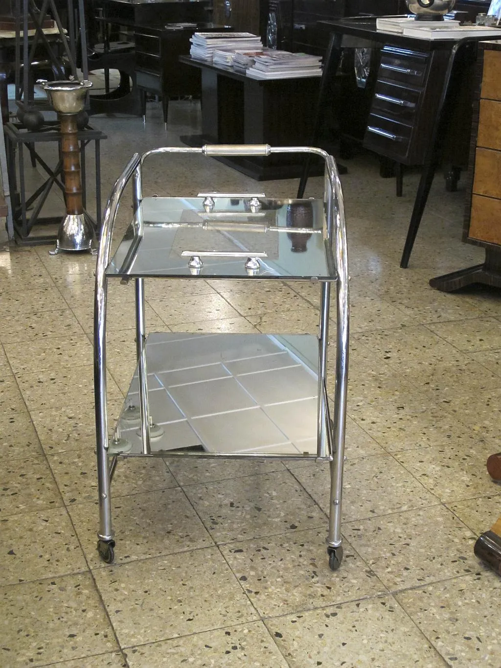 Carrinho de coquetel antigo com duas prateleiras e rodas em um ambiente elegante.