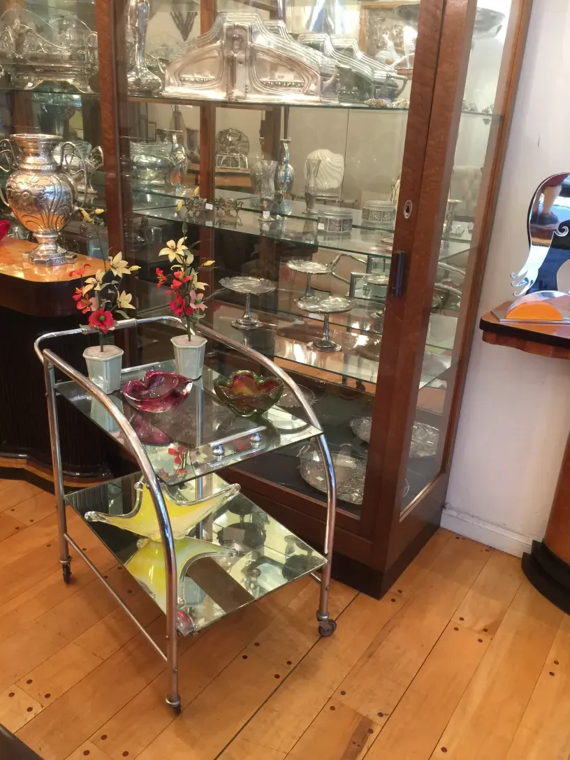 Antique cocktail trolley with floral decoration and glass. Elegant setting.