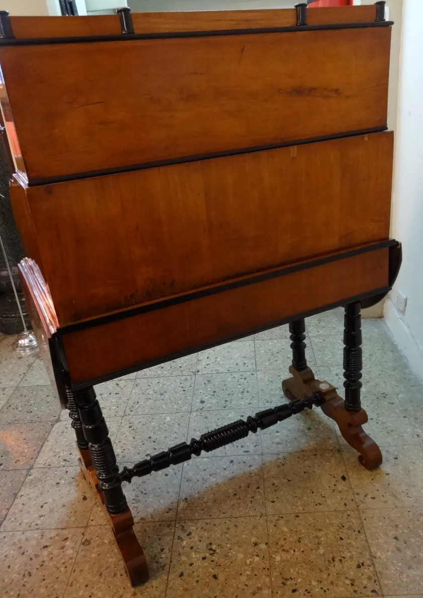 Escritorio antiguo de madera con un atril negro, en un ambiente acogedor.