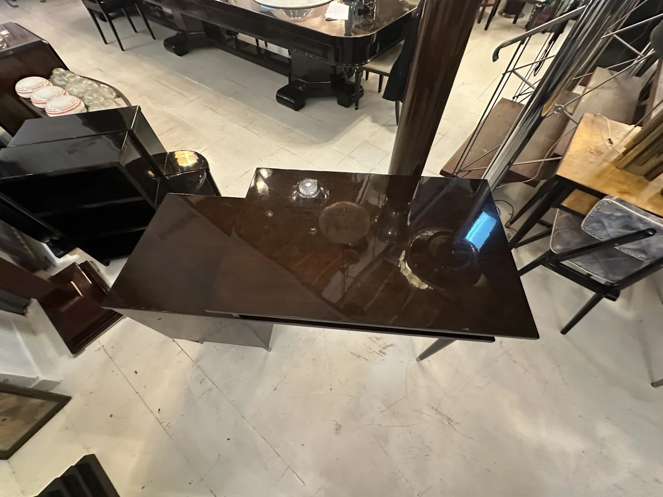 Scrivania antica brillante in un ambiente contemporaneo, con mobili scuri attorno.