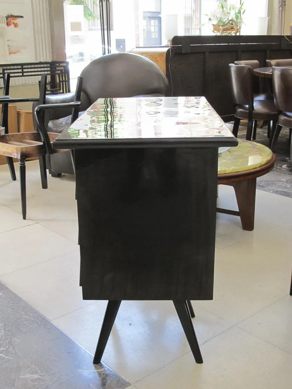 Antique desk with a shiny finish and tall legs in a cozy setting.