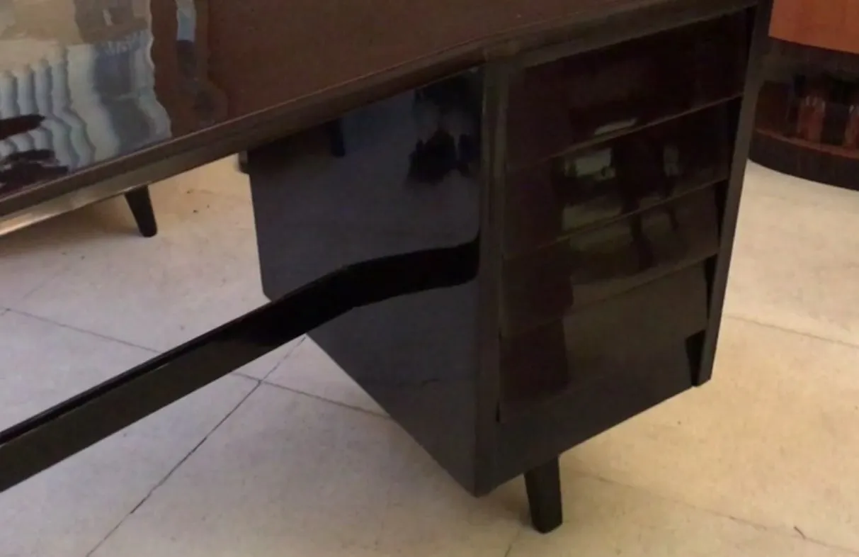 Antique desk with a shiny finish and subtle drawer handles in the surroundings.