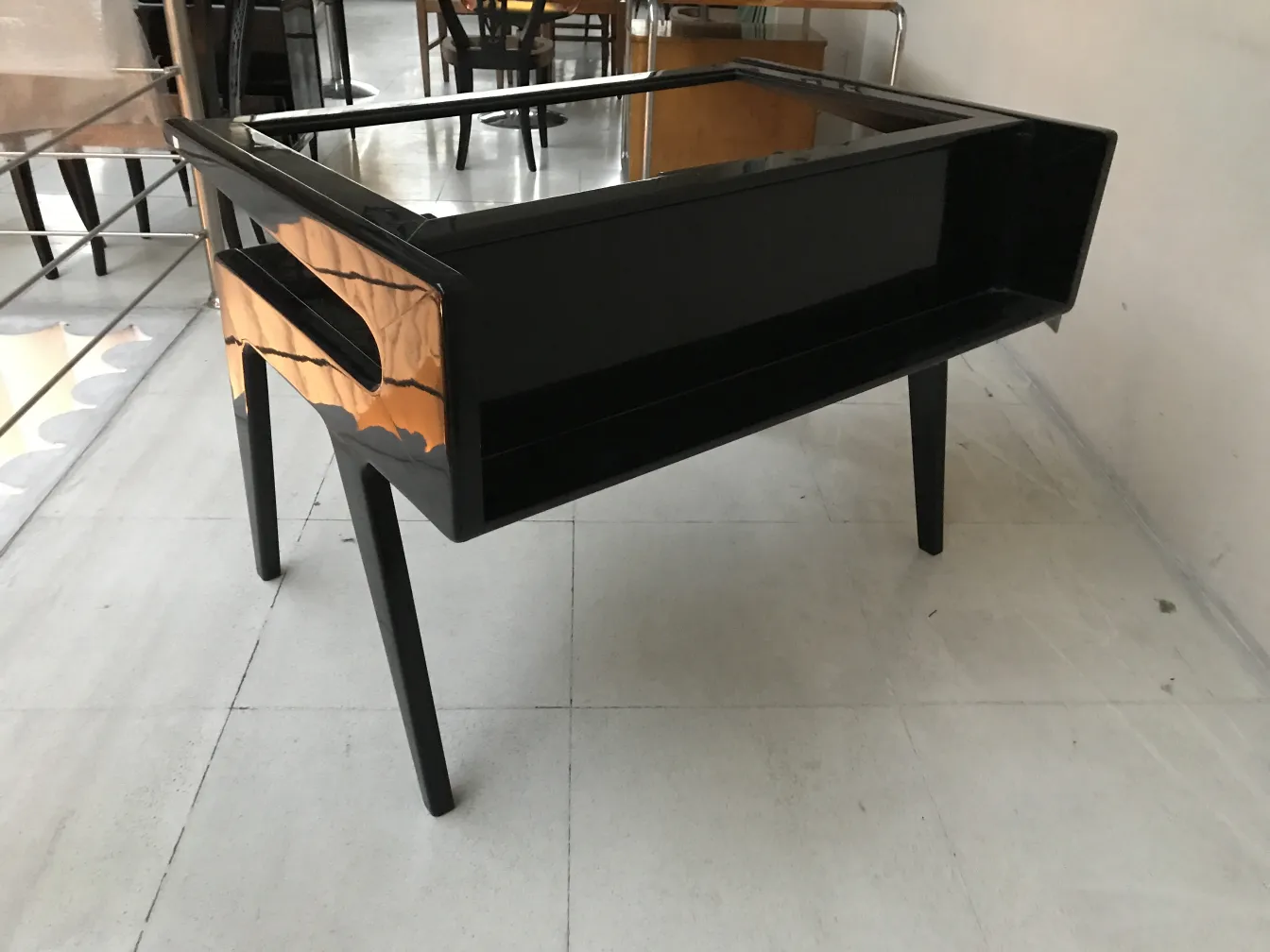 Antique black desk with glass top in a minimalist setting.