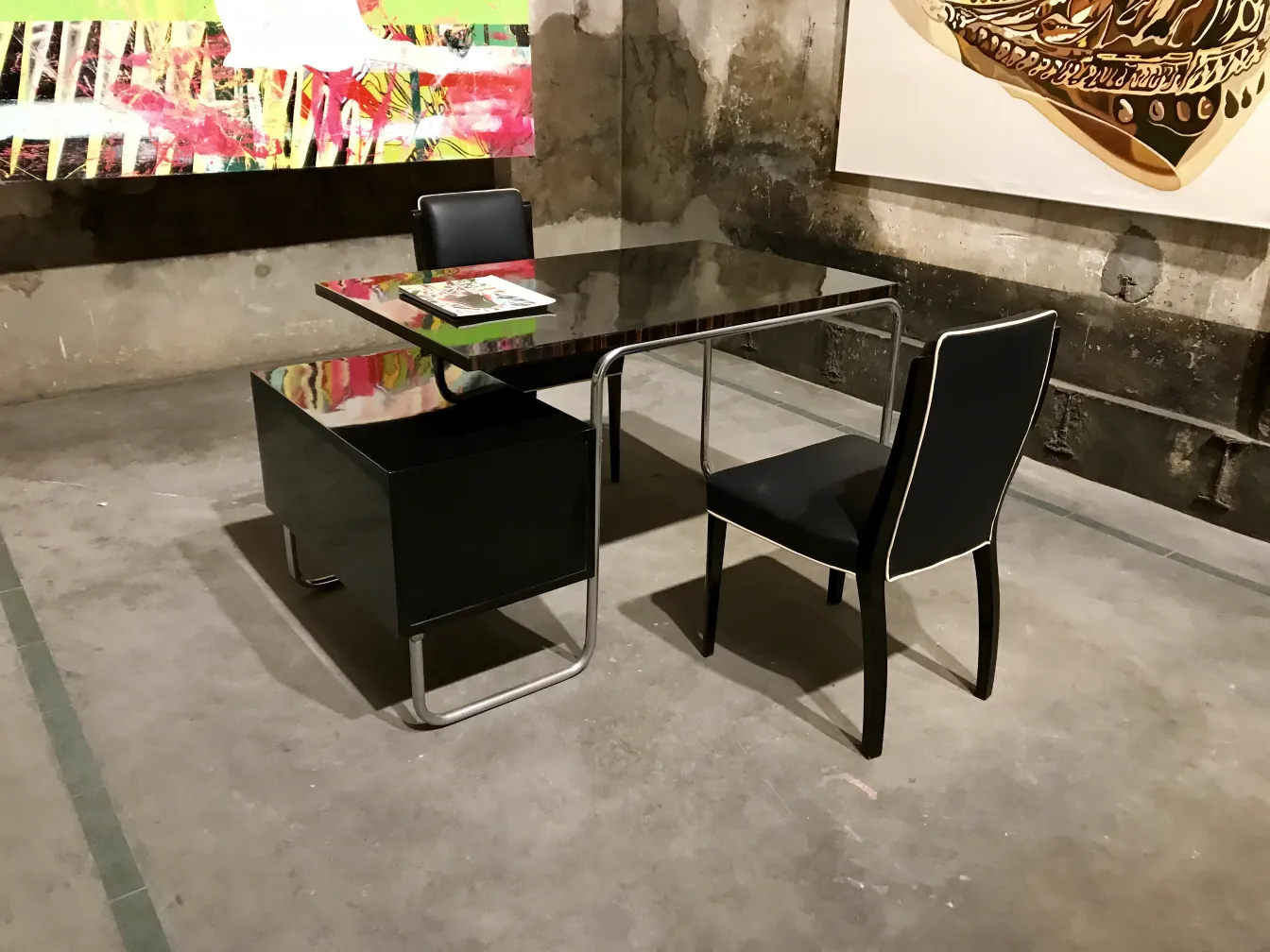 Alter Schreibtisch mit schwarzer Oberfläche und Schublade, modernes künstlerisches Ambiente.