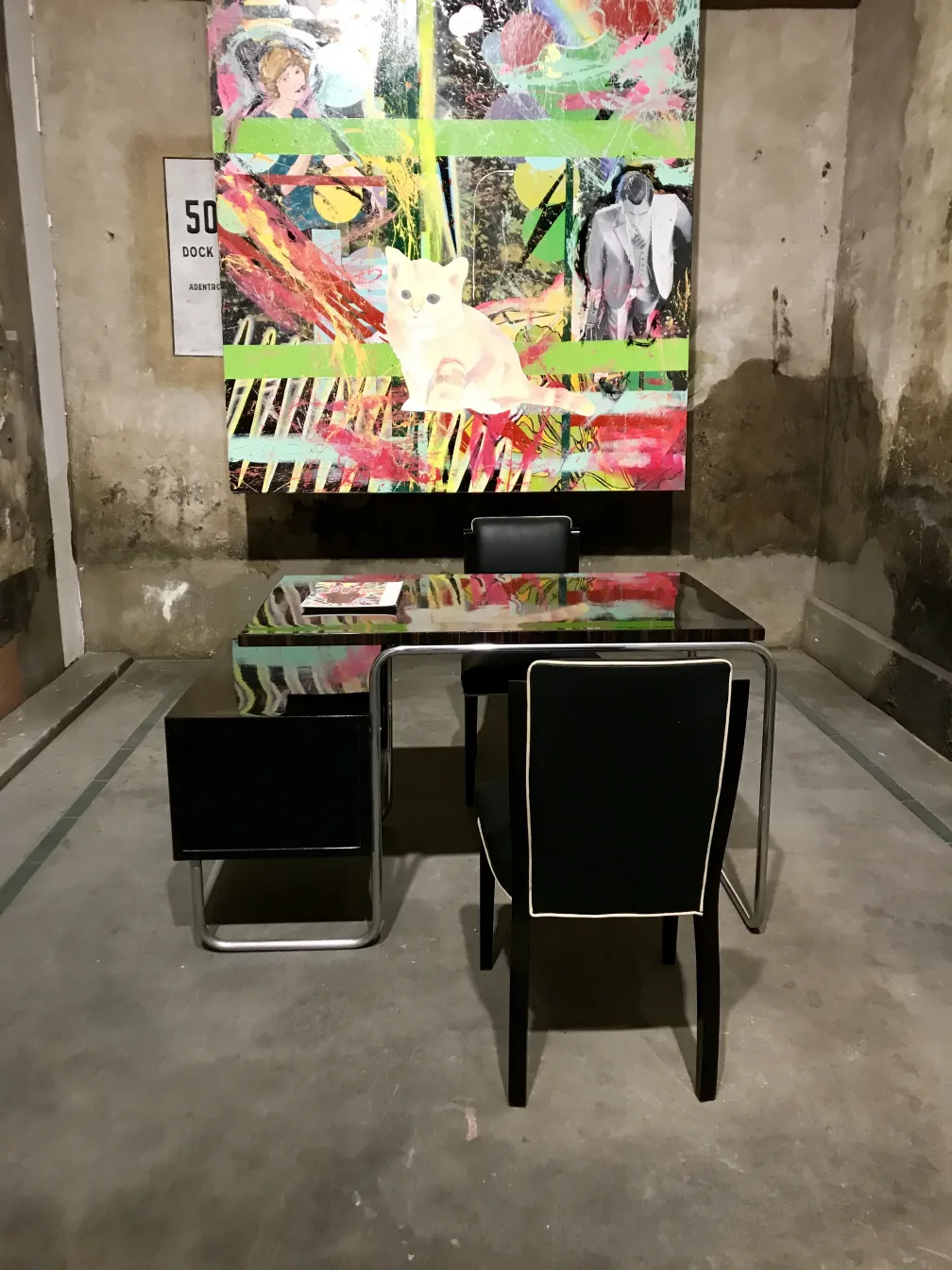 mesa antiga com cadeira e arte colorida nas paredes