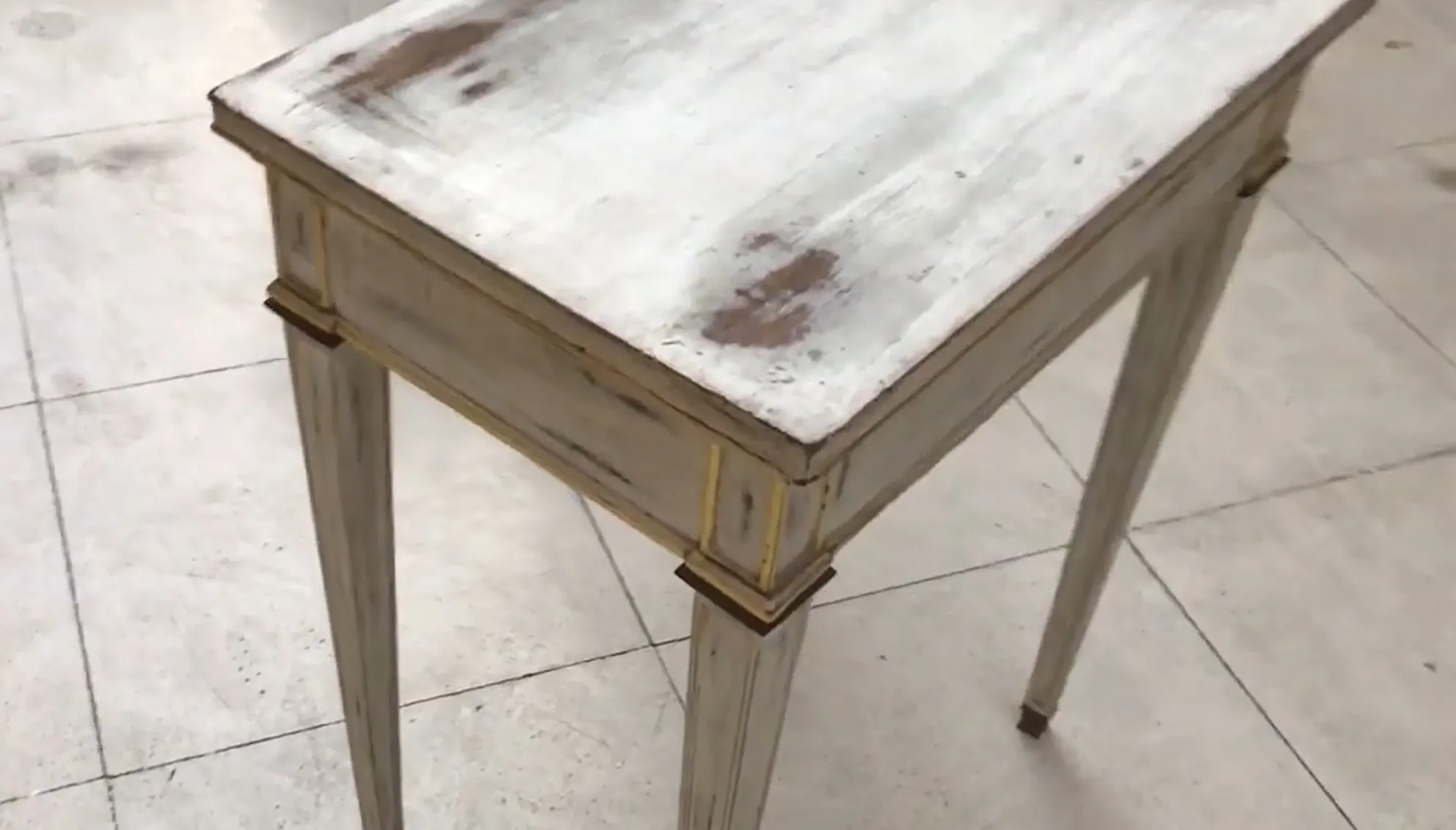 bureau ancien blanc avec pieds clairs et détails dorés, sur fond clair.