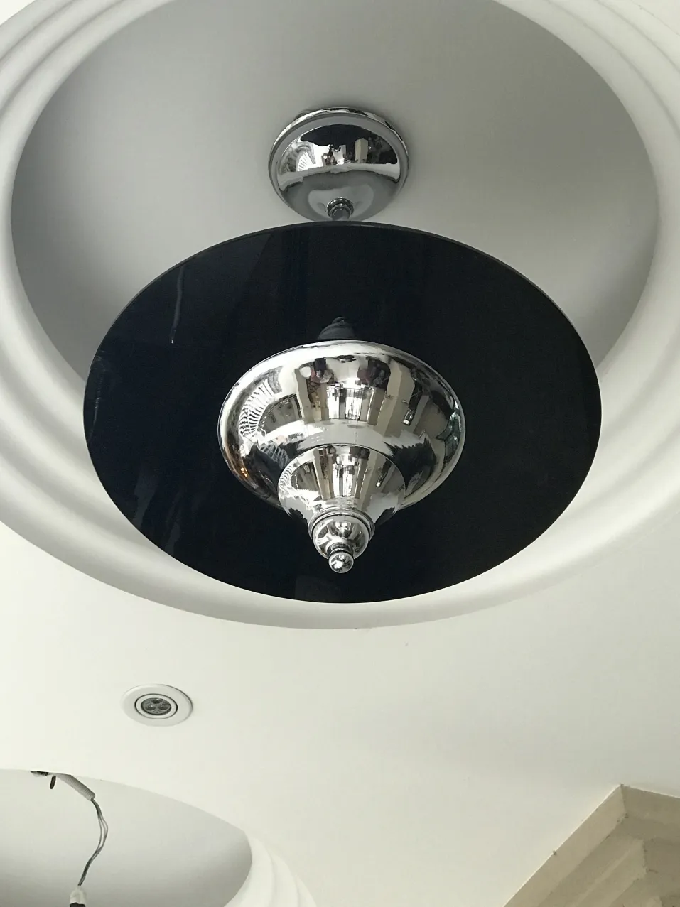 Lampada a sospensione antica nera e lucida, montata su un soffitto bianco.