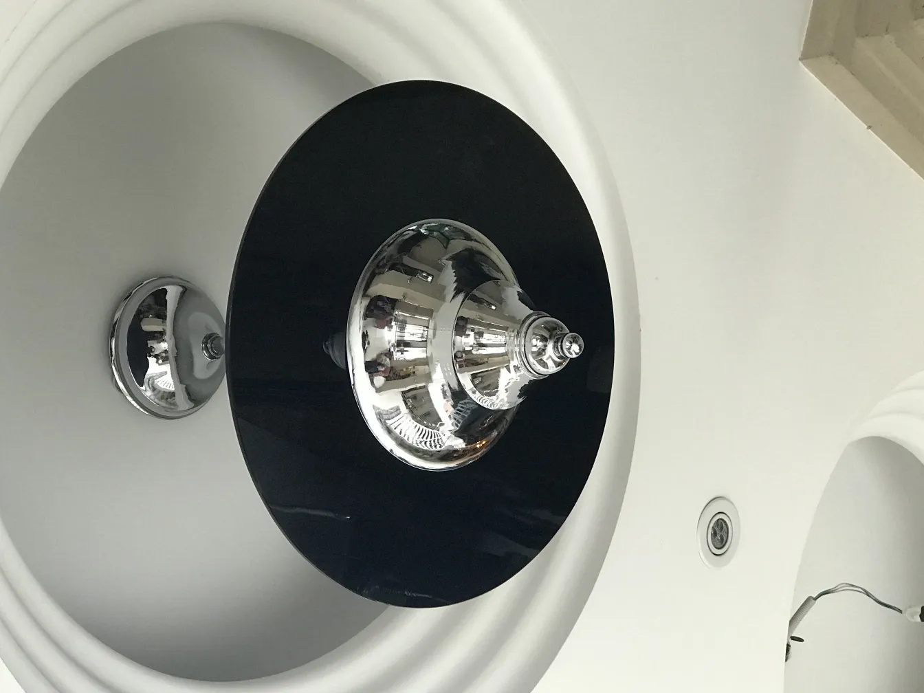 Lustre ancien avec un design noir et chromé, installé dans un environnement moderne.