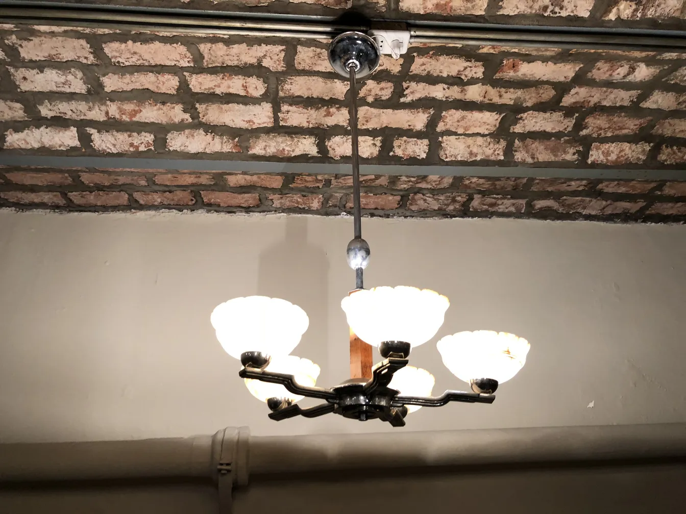 Lâmpada de teto antiga com luzes brancas em ambiente rústico.