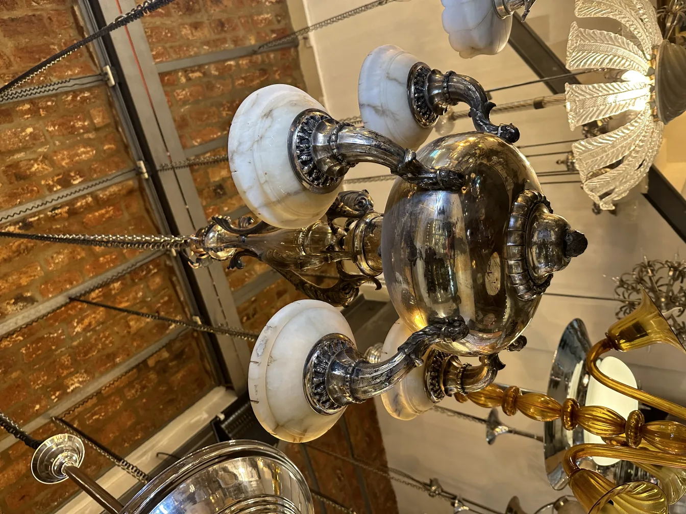 مصباح معلق قديم بقاعدة معدنية وأغطية رخامية في بيئة تحف.