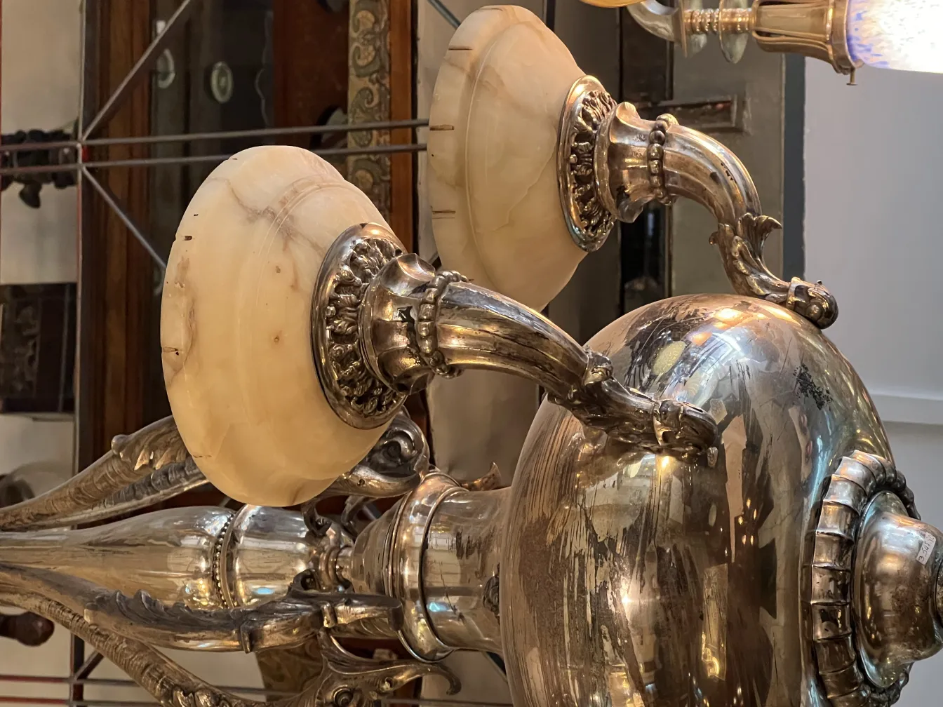 Lustre ancien avec des bras courbés élégants, éclairant un cadre classique.