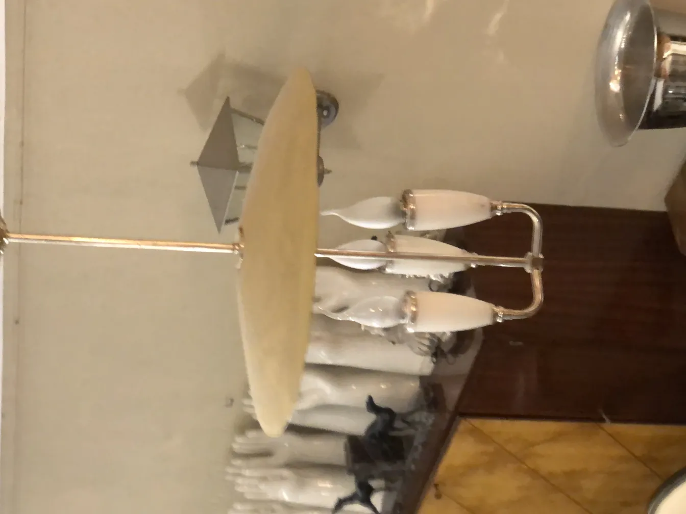 Lampada a sospensione antica con tre luci bianche in un ambiente classico.