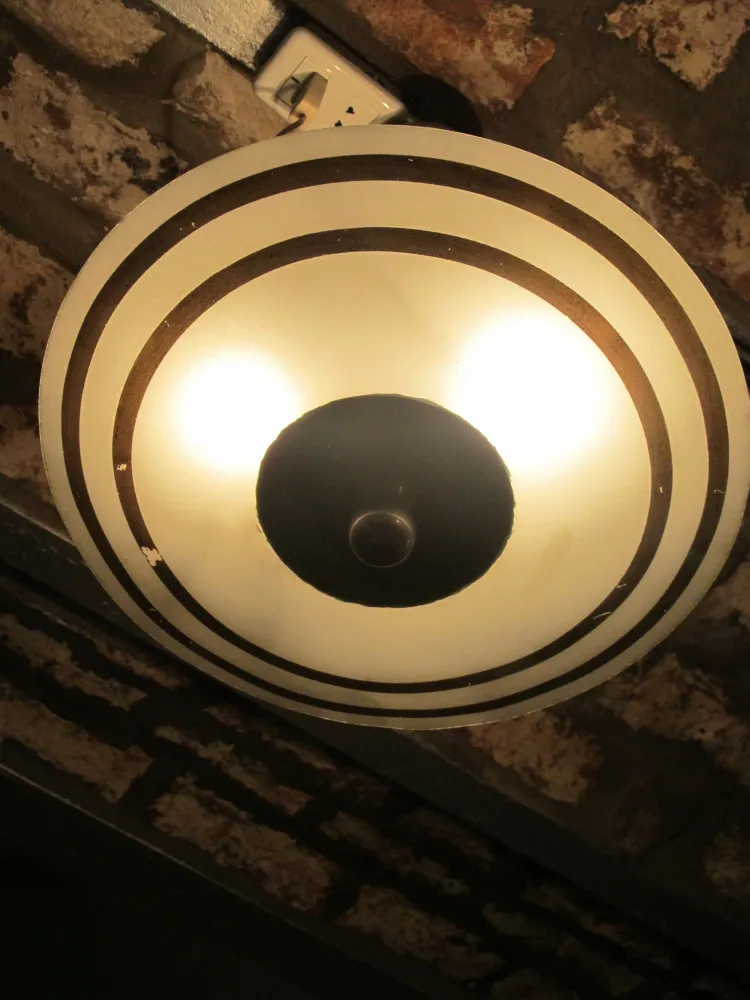 Lampada a sospensione antica con un design circolare e dettagli in bianco e nero, atmosfera accogliente.