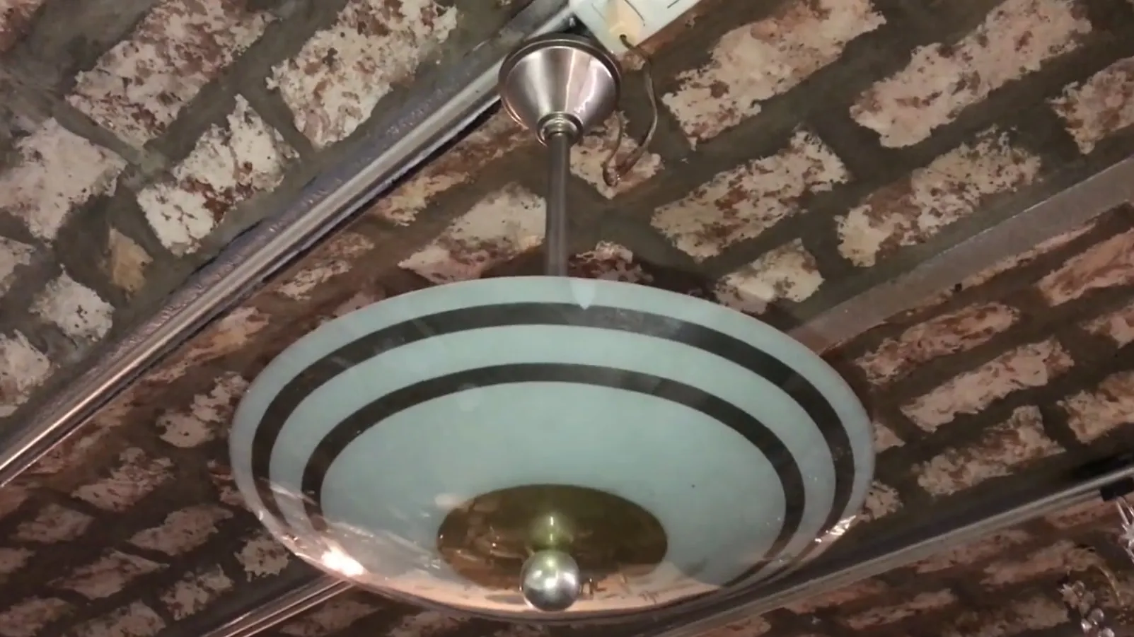 Lampada a sospensione antica con design elegante in ambiente rustico.