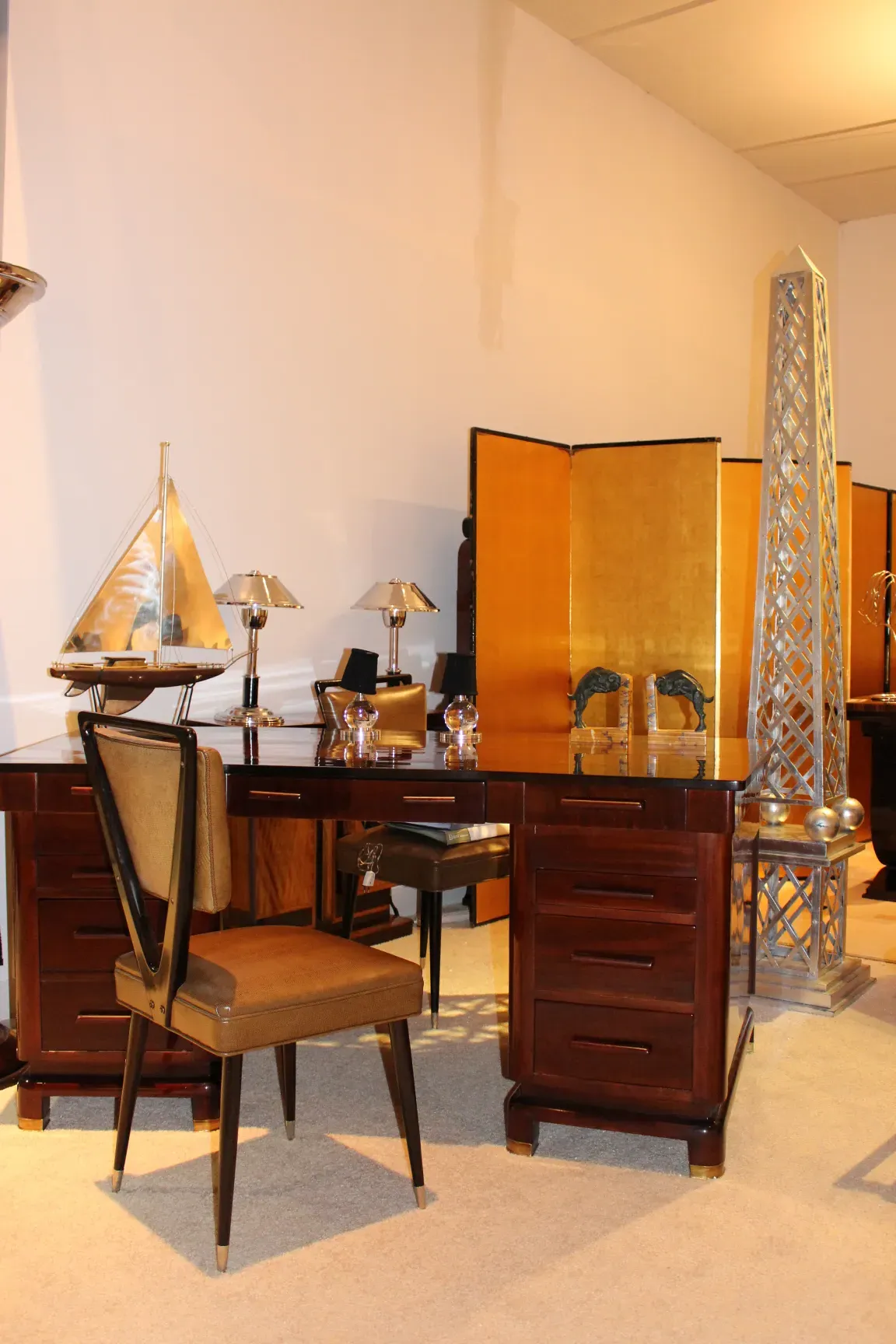 Antique wooden desk with lamps and chairs in the background.