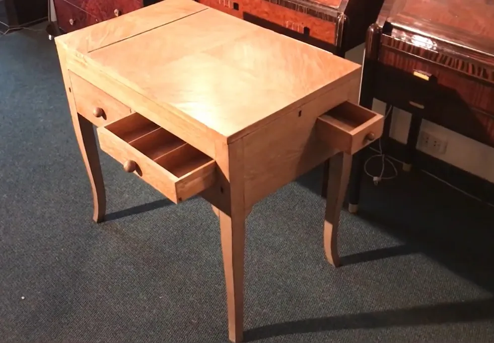 목재 앤틱 책상, 두 개의 서랍이 보임, 아늑한 환경에 배치됨.