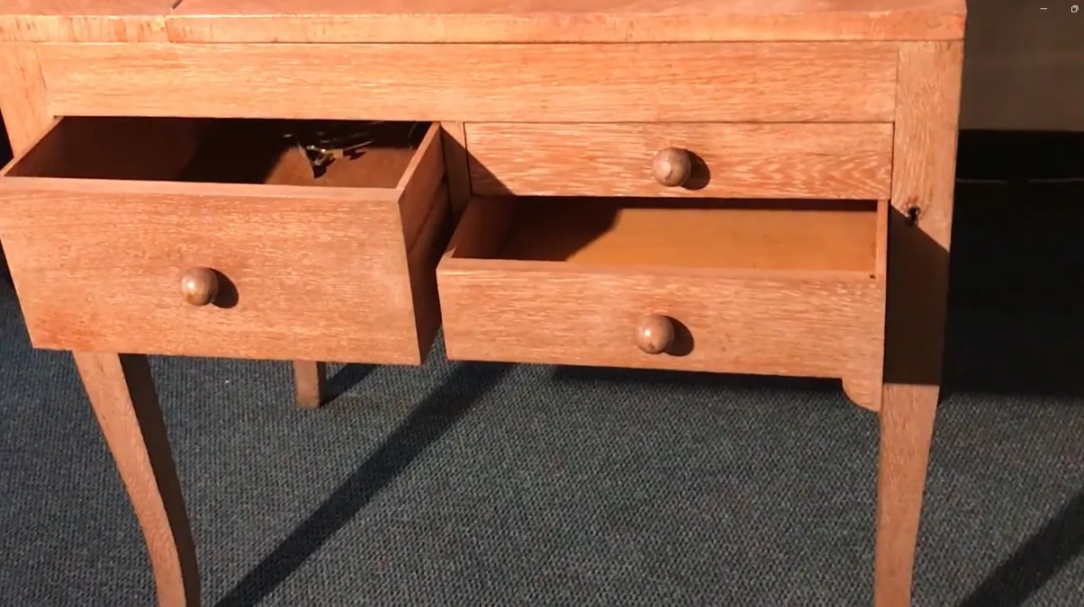 Antique wooden desk with two open drawers and slender legs.