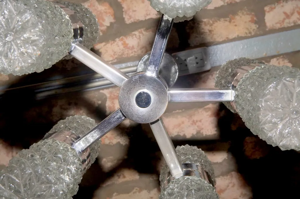 Antique hanging lamp with decorative crystals, viewed from below, rustic environment.