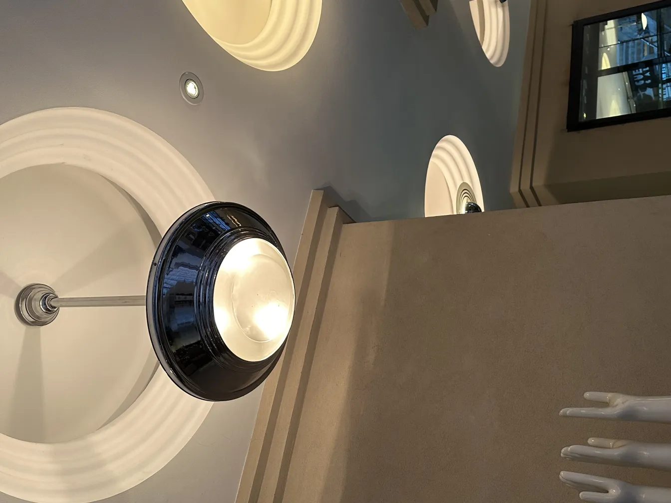 Antique hanging lamp with a sleek modern design, lights in the background.