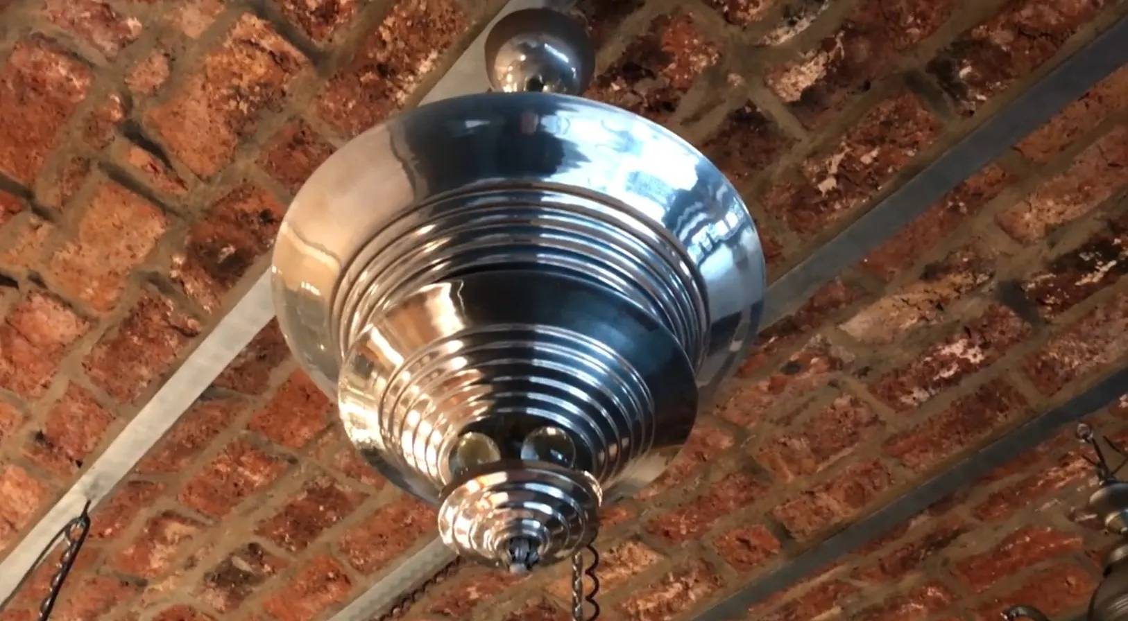 Lâmpada de teto antiga com design brilhante em ambiente de tijolo