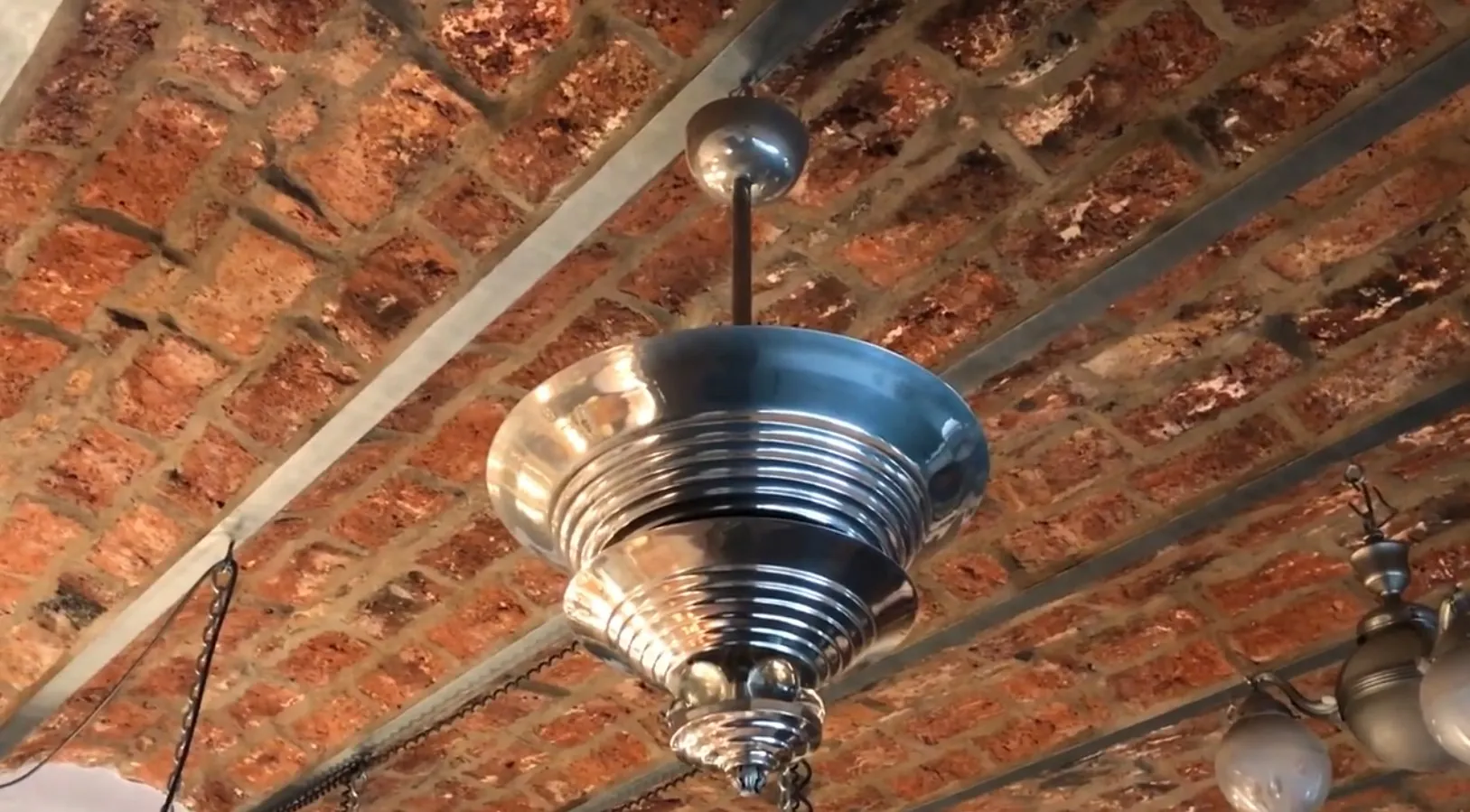 Antike Hängelampe mit metallischem Glanz in rustikalem Umfeld.