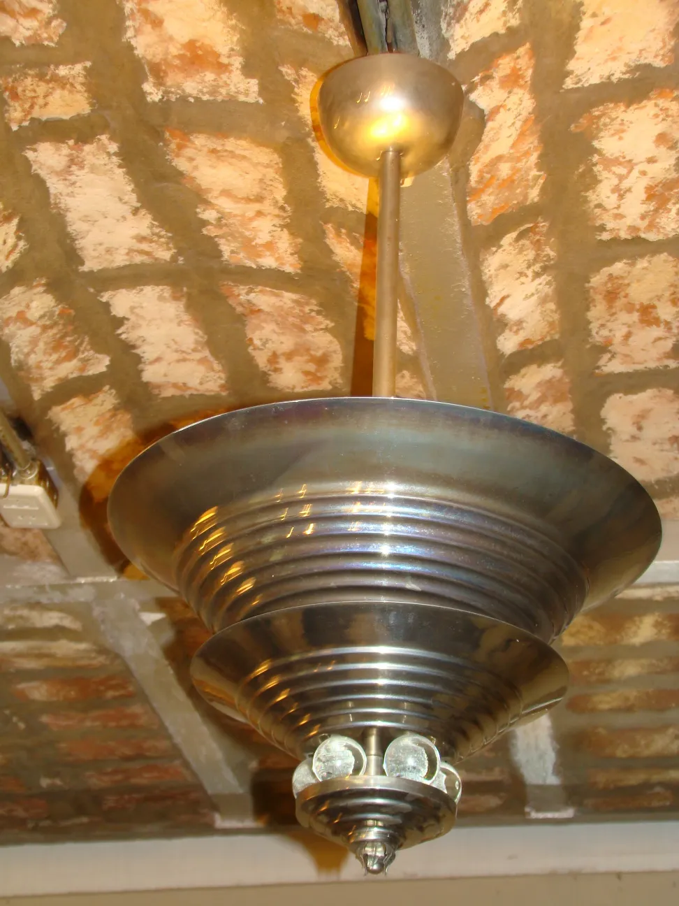 Antike Hängelampe mit einem besonderen Metalldesign, in einer rustikalen Umgebung aufgehängt.