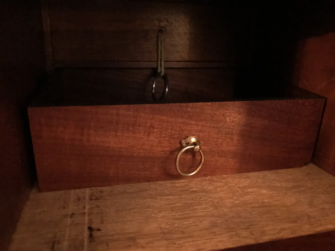 Escritorio antiguo con un tirador en forma de anillo y acabado de madera.