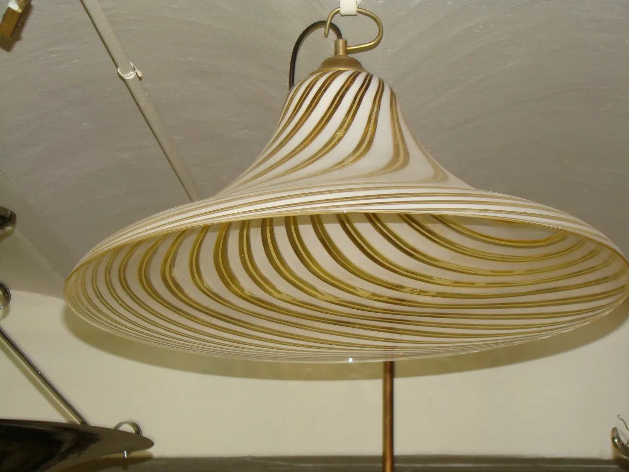 Antique hanging lamp with wavy design in light colors, warm ambiance.