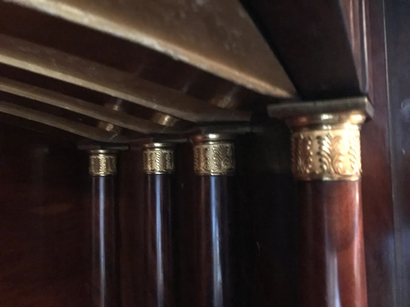 Antiker Schreibtisch mit Holzbeinen und goldenen Details an der Basis.